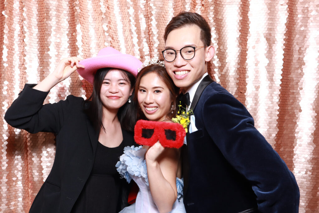 3 guests having tons of fun during a wedding reception party entertainment at hyde house in gloucester, posing against a blush sequins backdrop