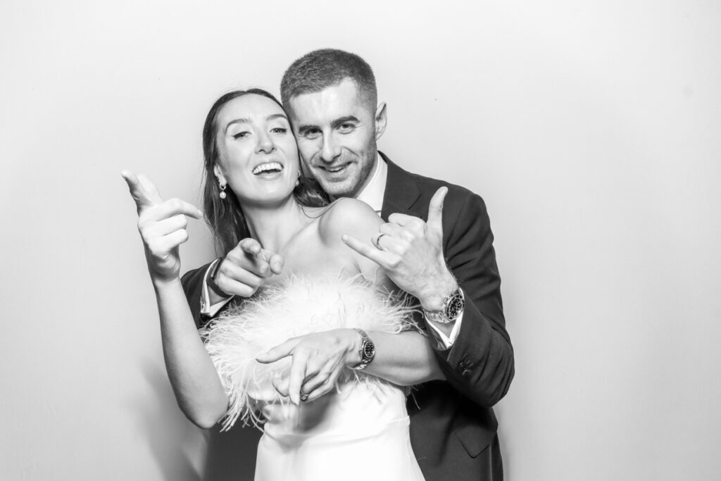 2 guests holding their glasses and posing against a white backdrop, for a gloucestershire party 