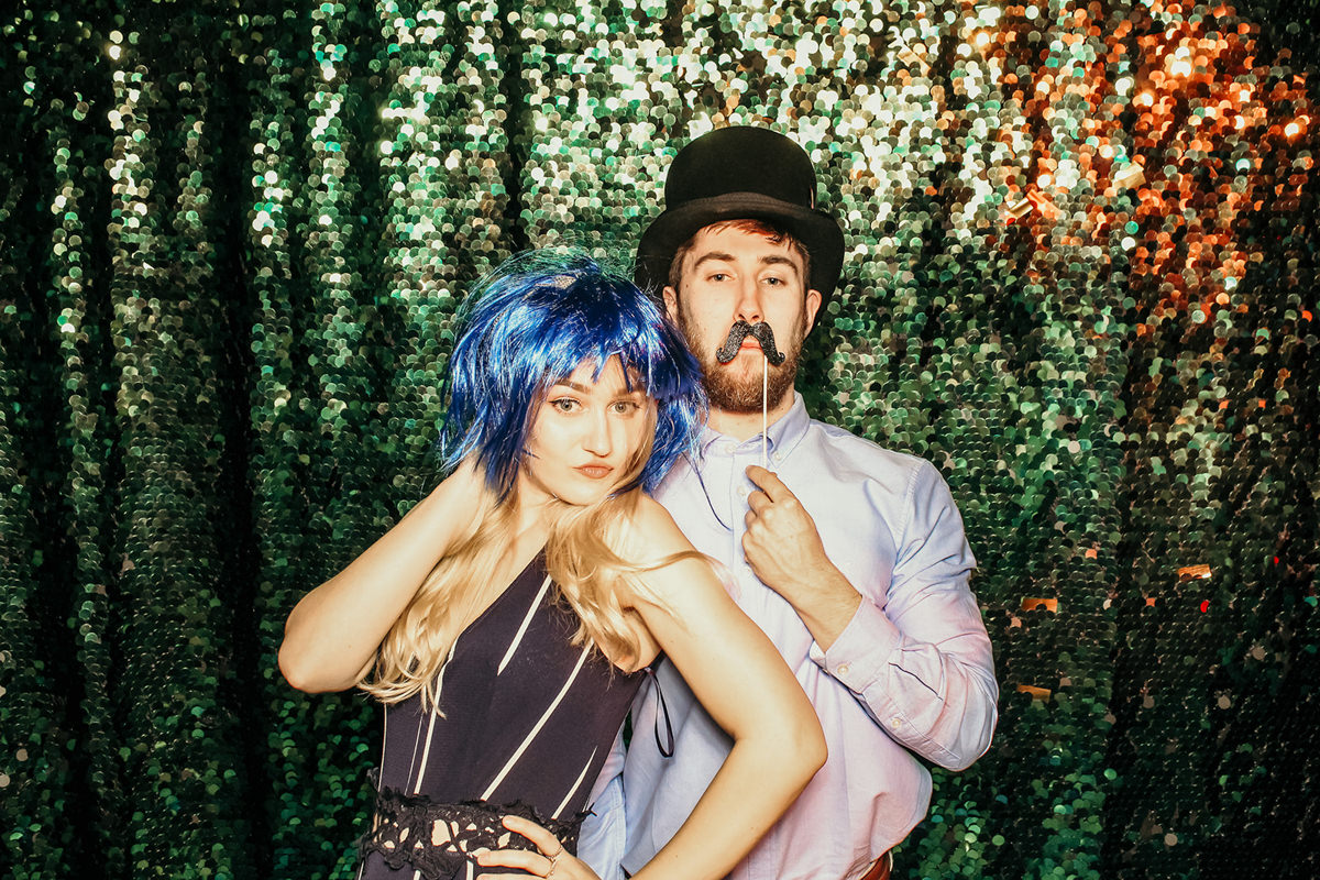 guests during wedding posting for a photo booth with green sequins backdrop