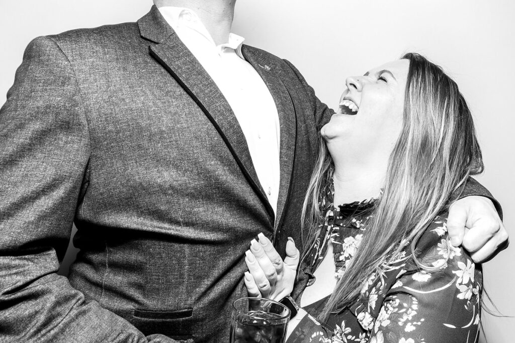 A joyful couple sharing a candid laugh, captured in a sleek black and white photo booth filter