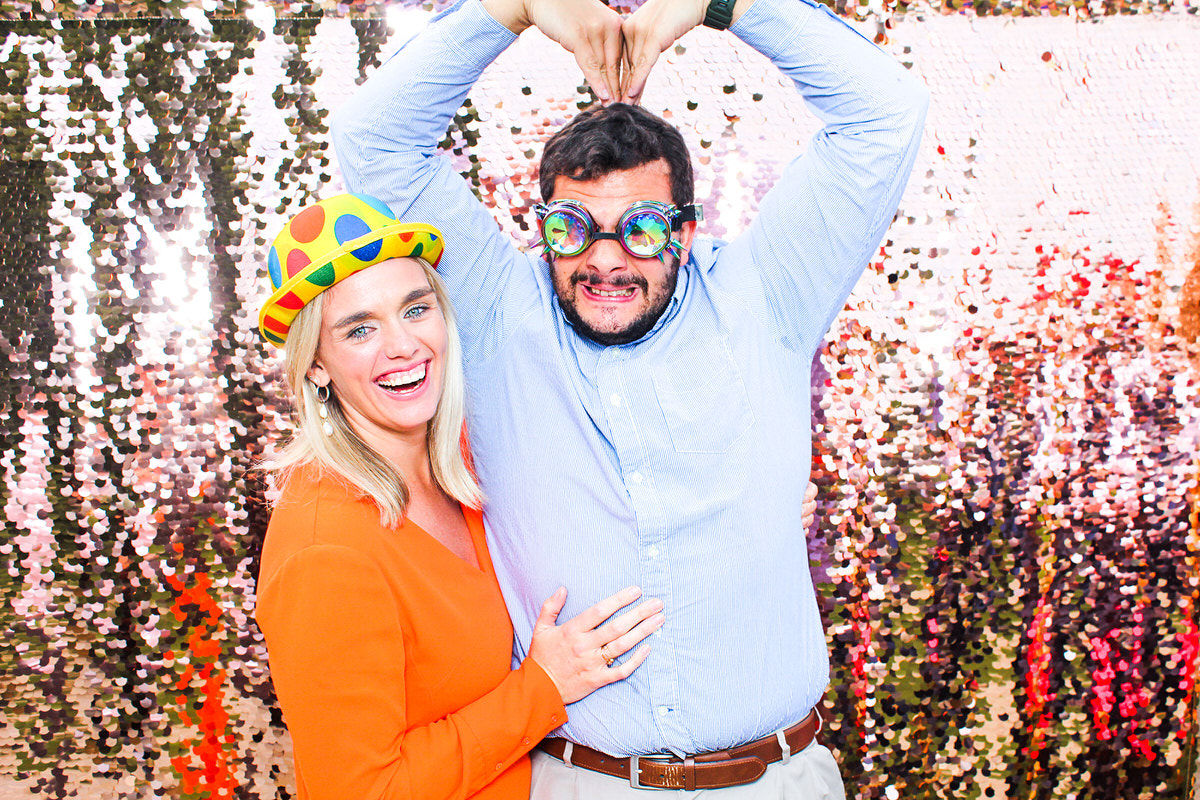 couple posing silly for mad hat photo booth in cotswolds during a wedding