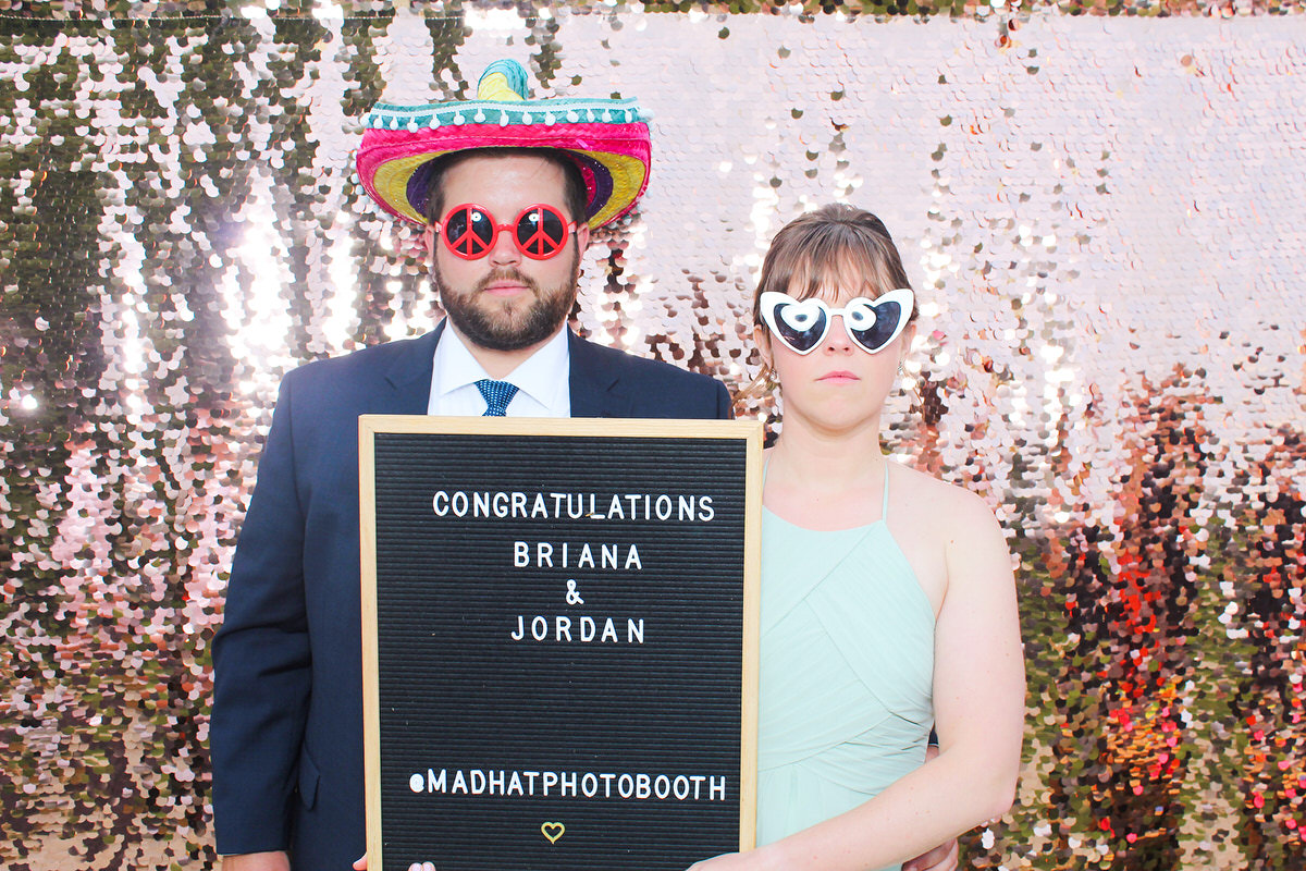 fun couple holding a board with bride and groom names during a photo booth event in cotswolds