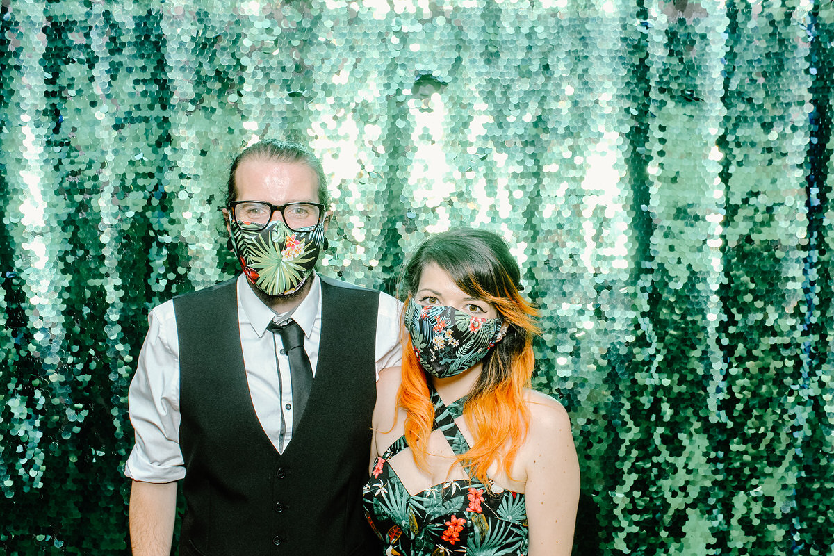 guests posing in front of a green sequins backdrop during a photo booth event at Redhouse Barn