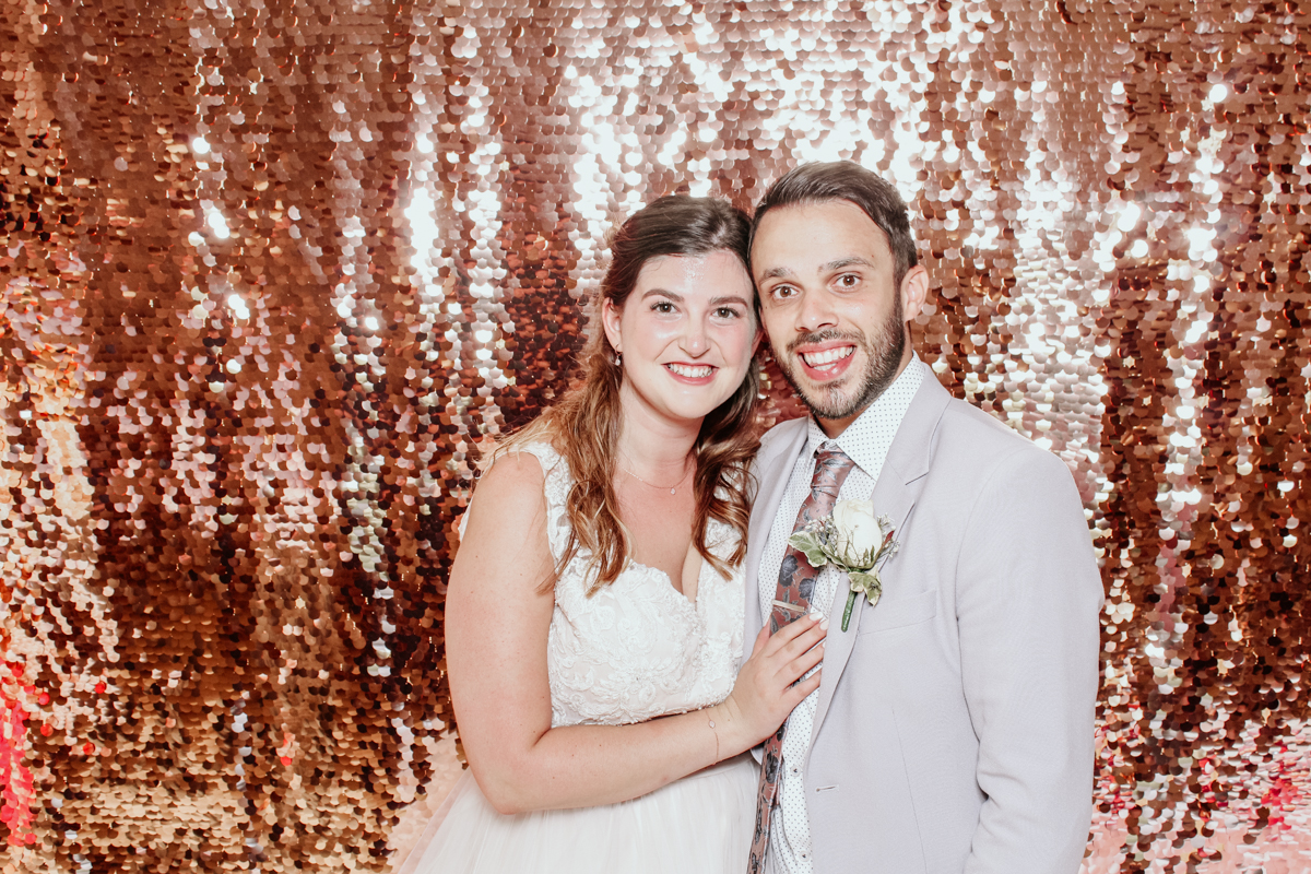 bride and groom posing for mad hat photo booth at kingscote barn wedding venue