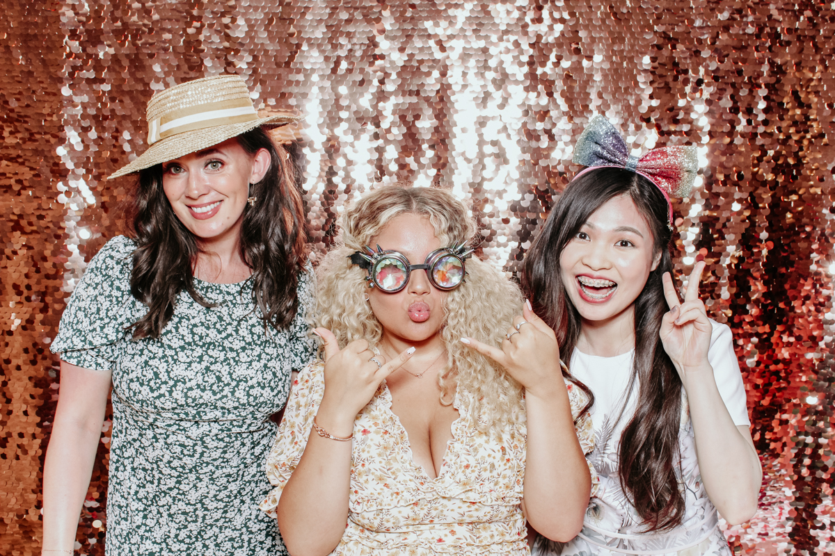 girls posing with props for photo booth event at kingscote barn with rose sequins backdrop