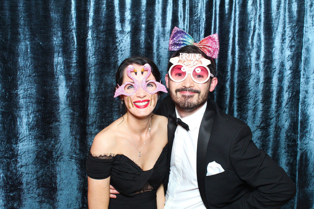 couple wearing props with a velvet blue backdrop for a cotswolds photo booth event