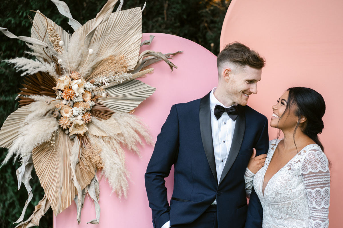 bride and groom posing with modern photo booth arches during a wedding day