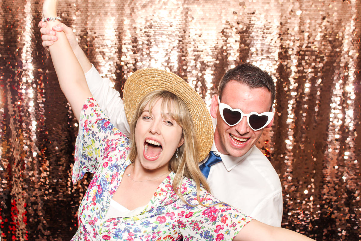 fun couple with props and sequins backdrop during a capstone barn event