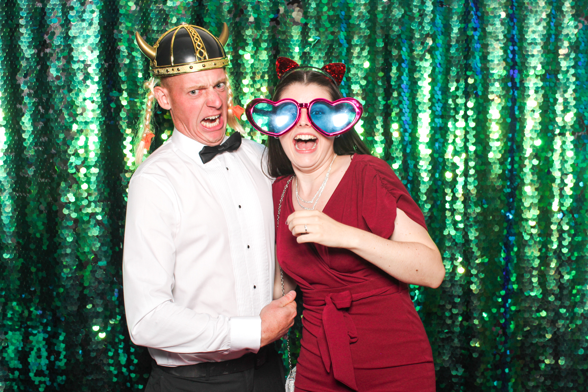 couple wearing props with a green sequins backdrop during a Manor wedding
