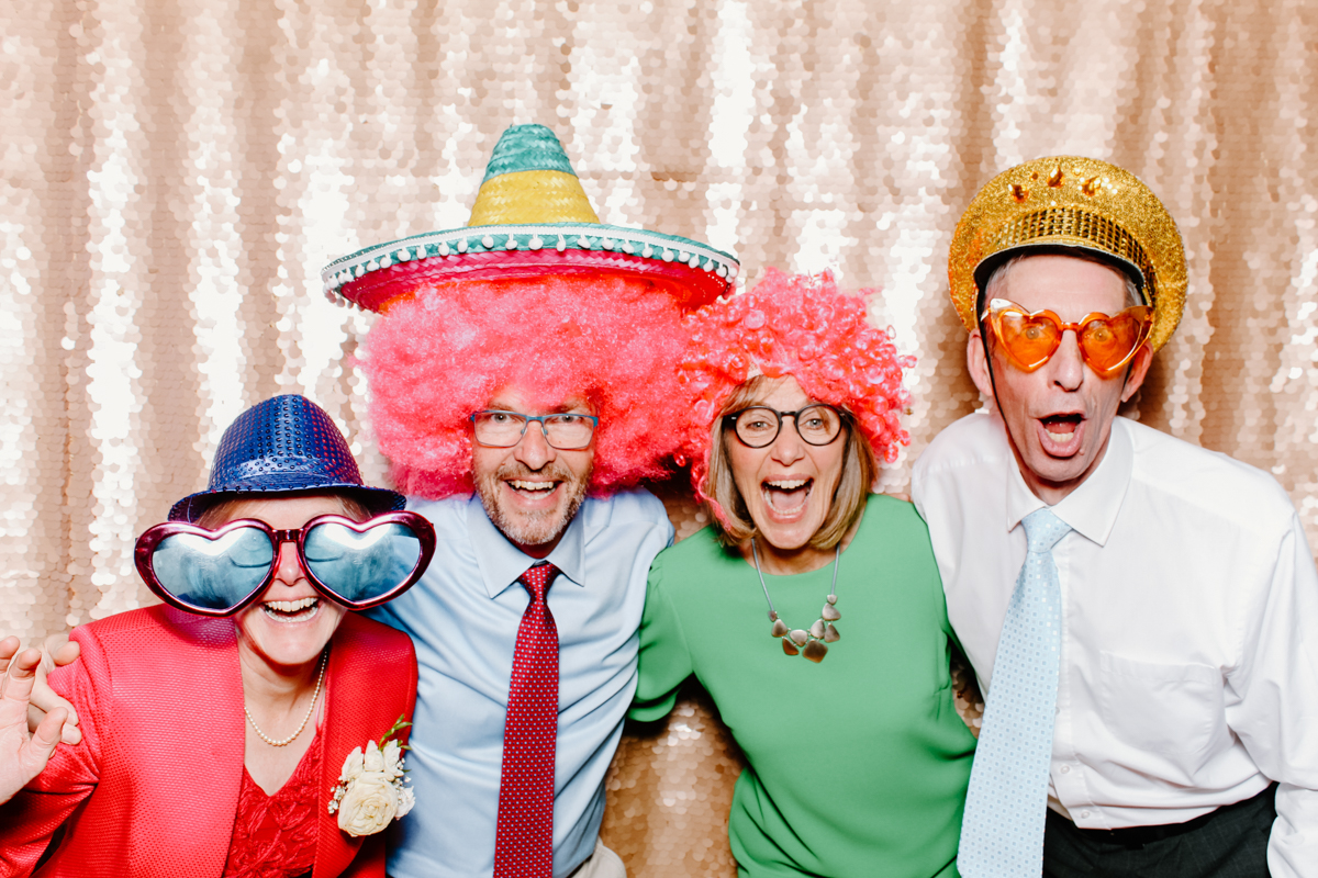 fun group photo for a cotswolds wedding in Gloucestershire with guests wearing props and hats and wigs and having fun