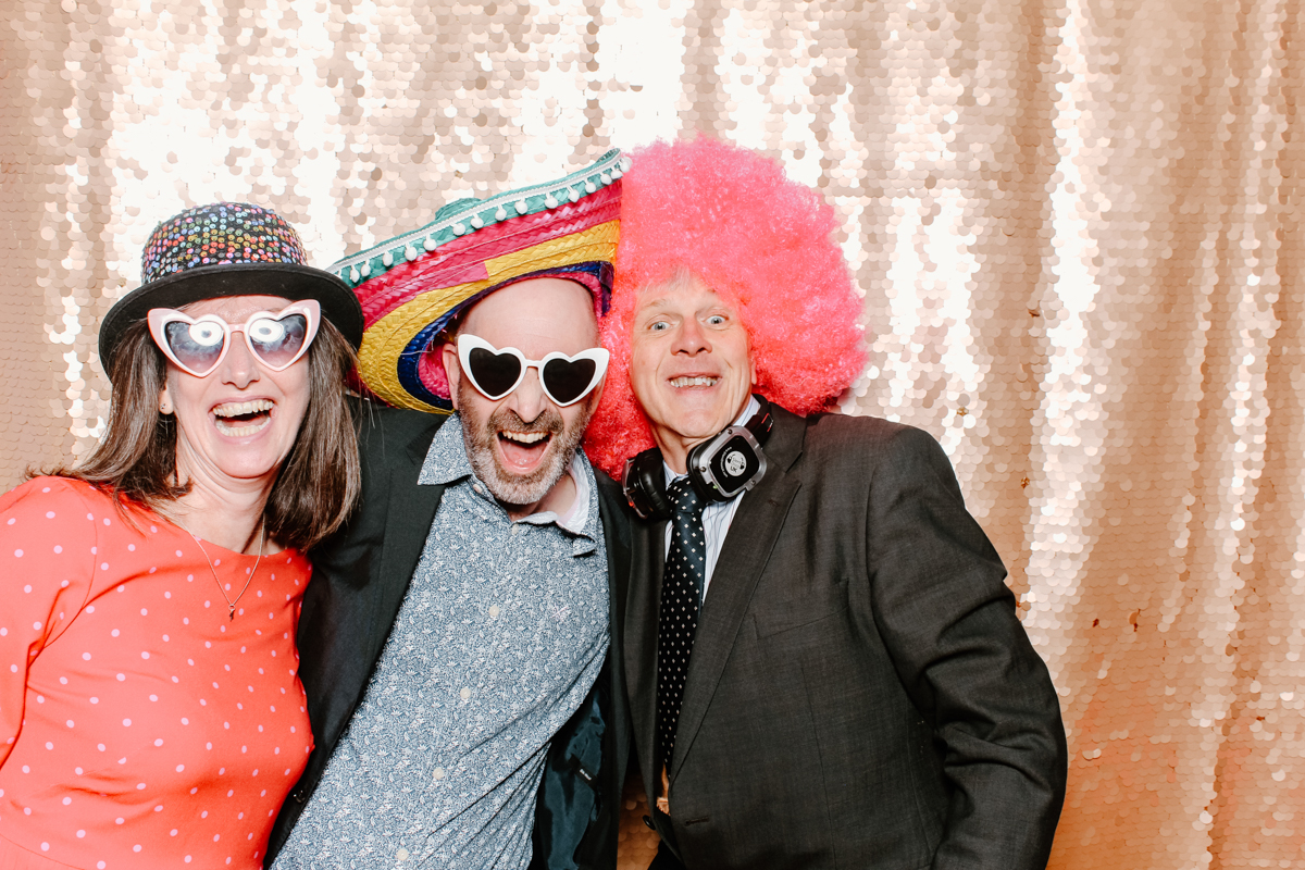 Gloucestershire photo booth hire for a corporate party entertainment with guests wearing props and posing against a blush sequins backdrop