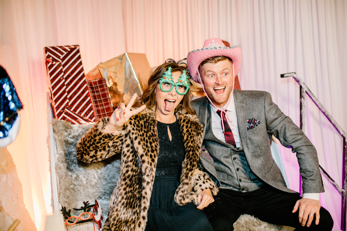 couple posing on a sledge with christmas presents in the background 