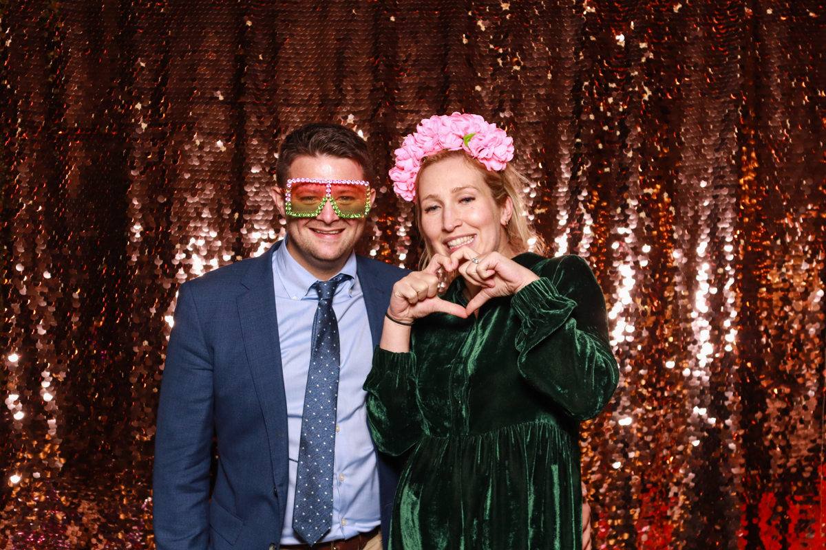 couple posing for cotswolds photo booth hire with a rose gold sequins backdrop