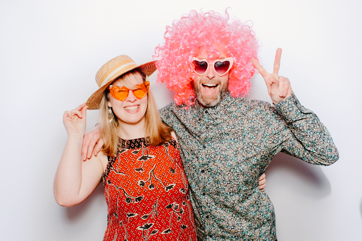 couple wearing hats and glasses for a photo booth photo at the swan hotel bibury