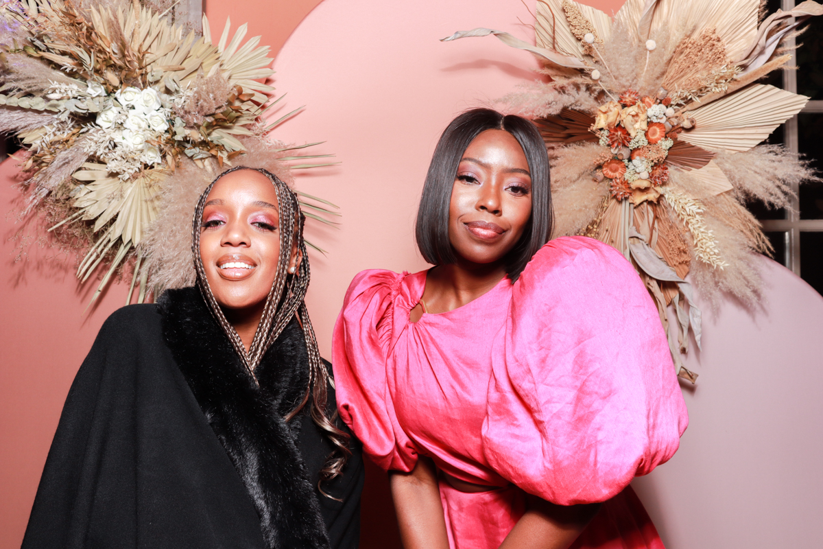 girls posing for photo booth with dried flower arrangements and pink backdrop