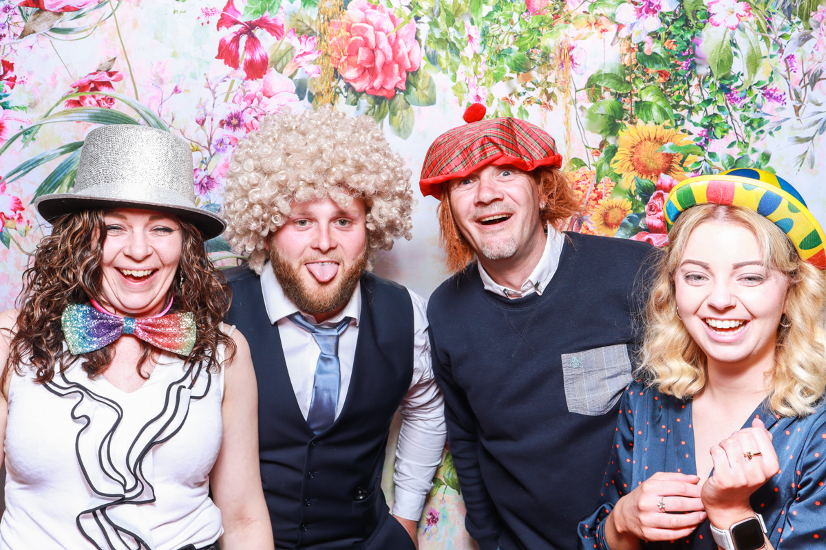 guests with floral backdrop behind, posing for a wedding photo booth hire cotswolds