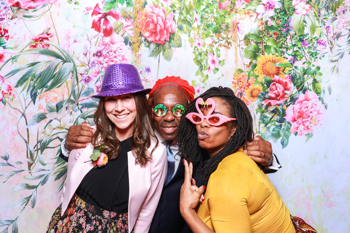 wedding guests with floral backdrop during a photo booth event in chipping norton cotswolds