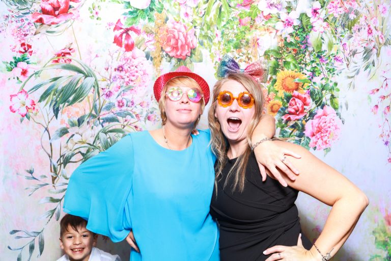 wedding guests using the wedding photo booth with a floral backdrop behind
