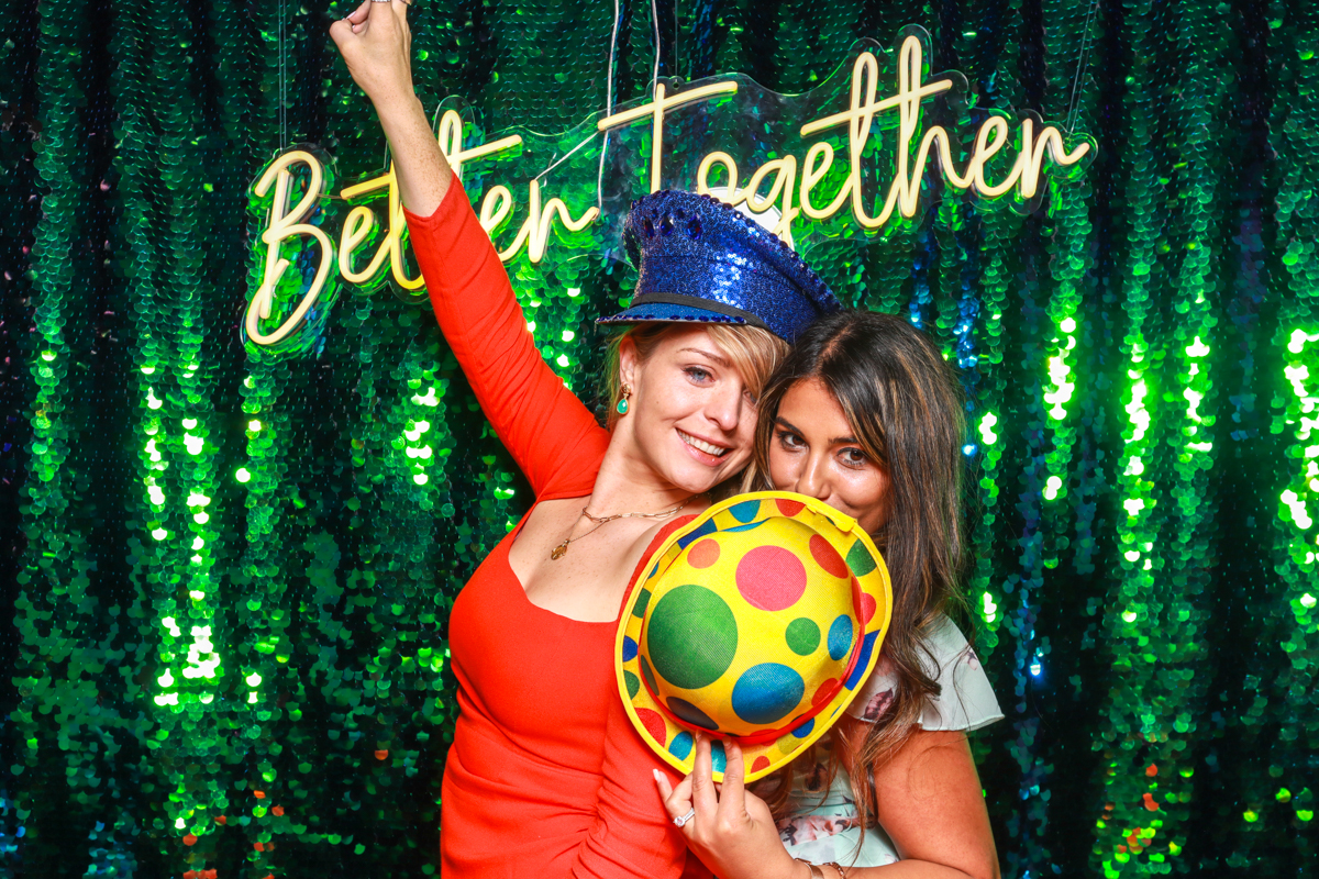 guests posing with the better together neon sign during a cotswolds wedding