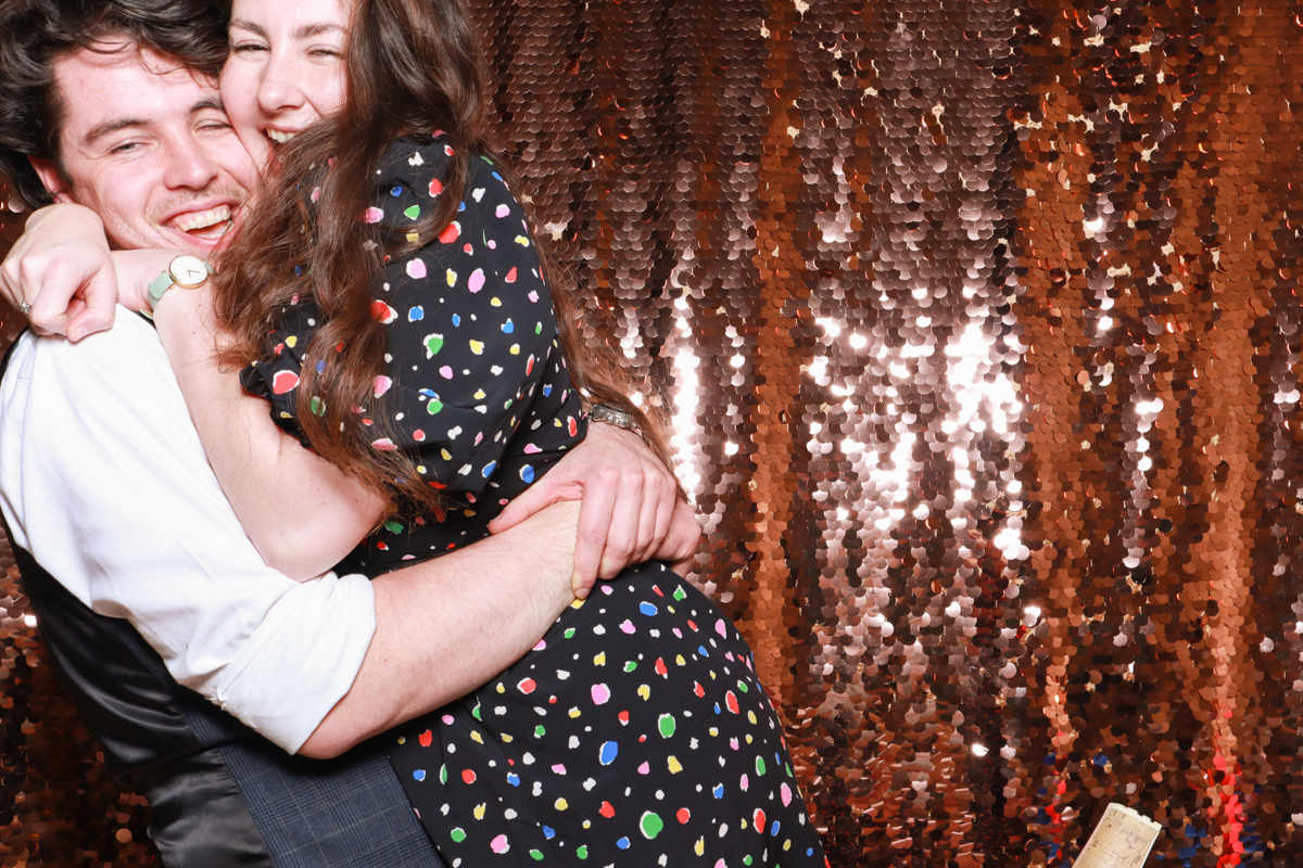 couple hug with the sequins backdrop during a cotswolds wedding party