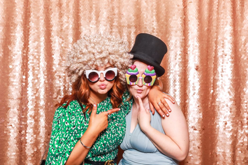 2 guests during a wedding party at Bredenbury Court posing for mad hat photo booth rental