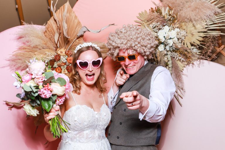 pink backdrop with dried flower arrangements for a photo booth setup