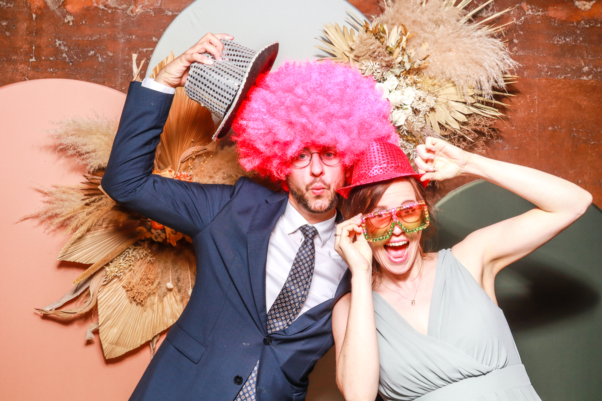 couple having fun posing against a modern arches backdrop in 3 colours, with dried flowers arrangements attached on, during a reception party