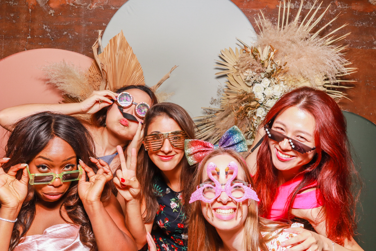 5 guests during a photo booth photography moment, posing against a modern arches backdrop in 3 colours, with dried flowers arrangements attached on, at elmore court