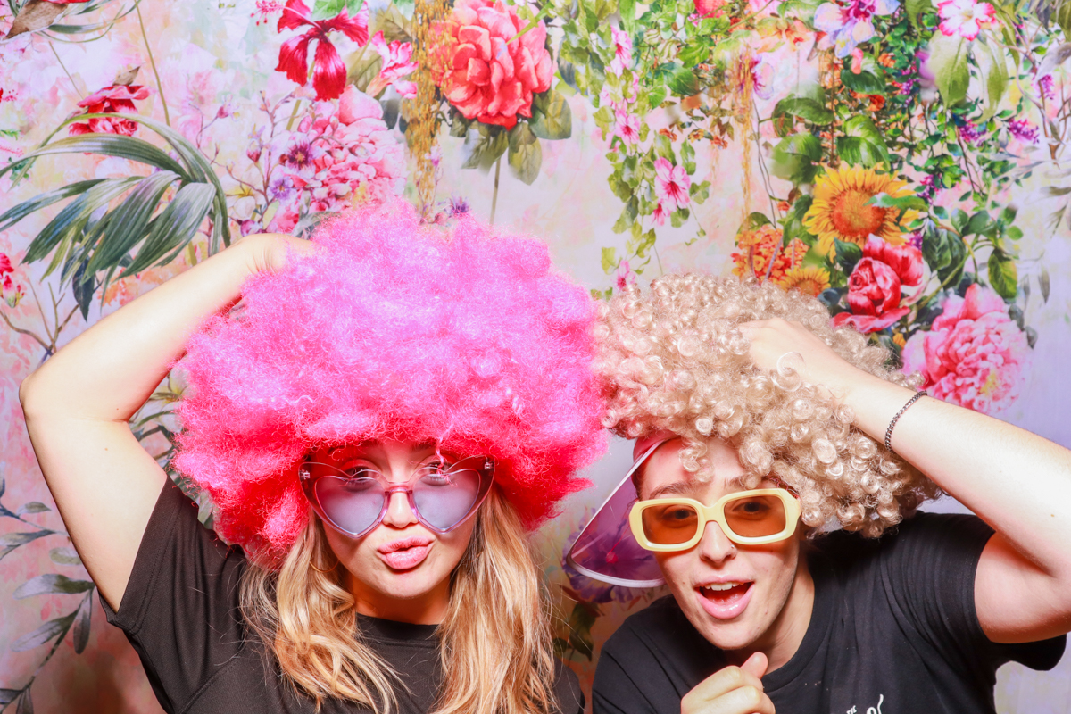 girls wearing fun gigs during a photo booth event for a corporate party