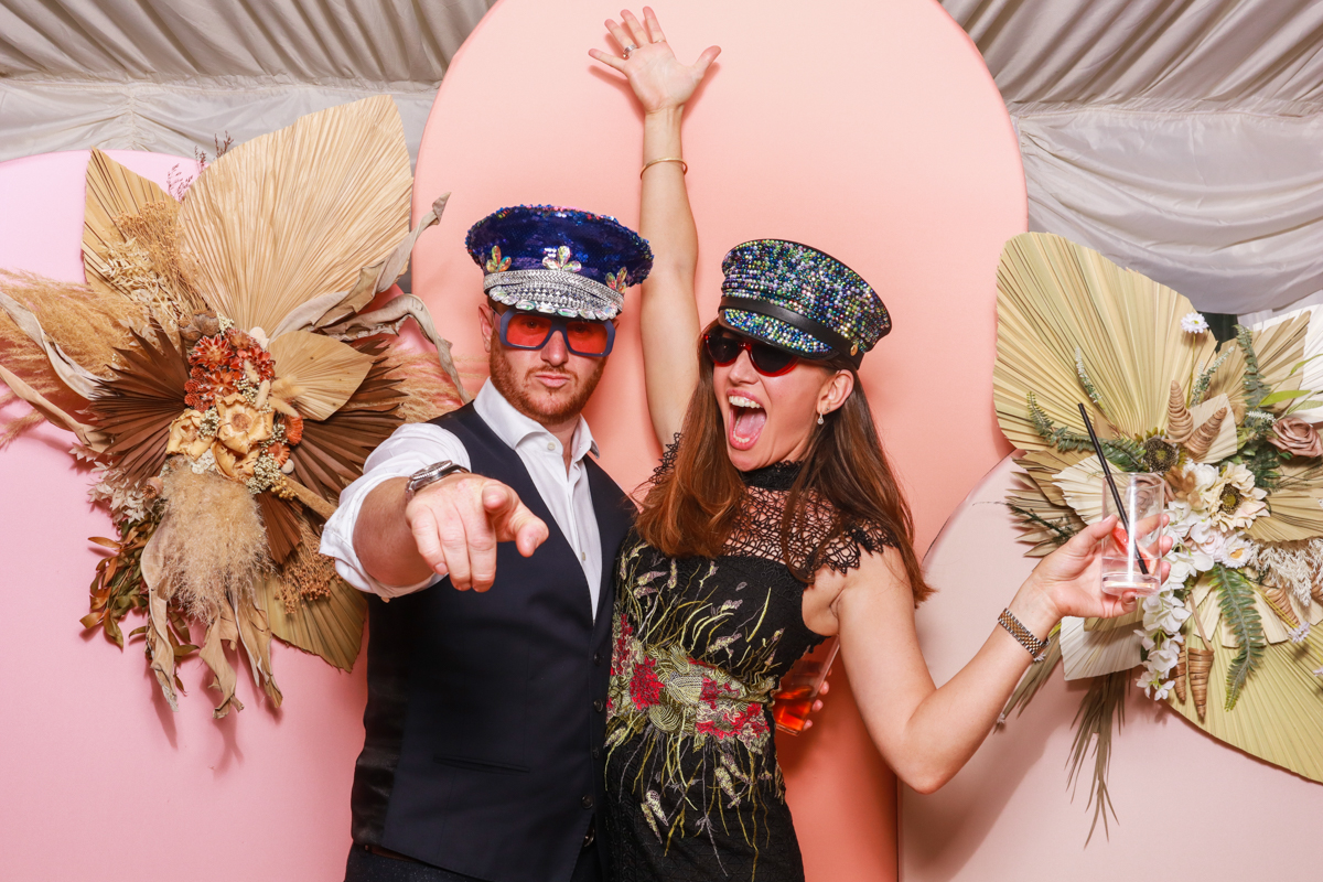 guests posing against a summer photo booth backdrop during a party entertainment 