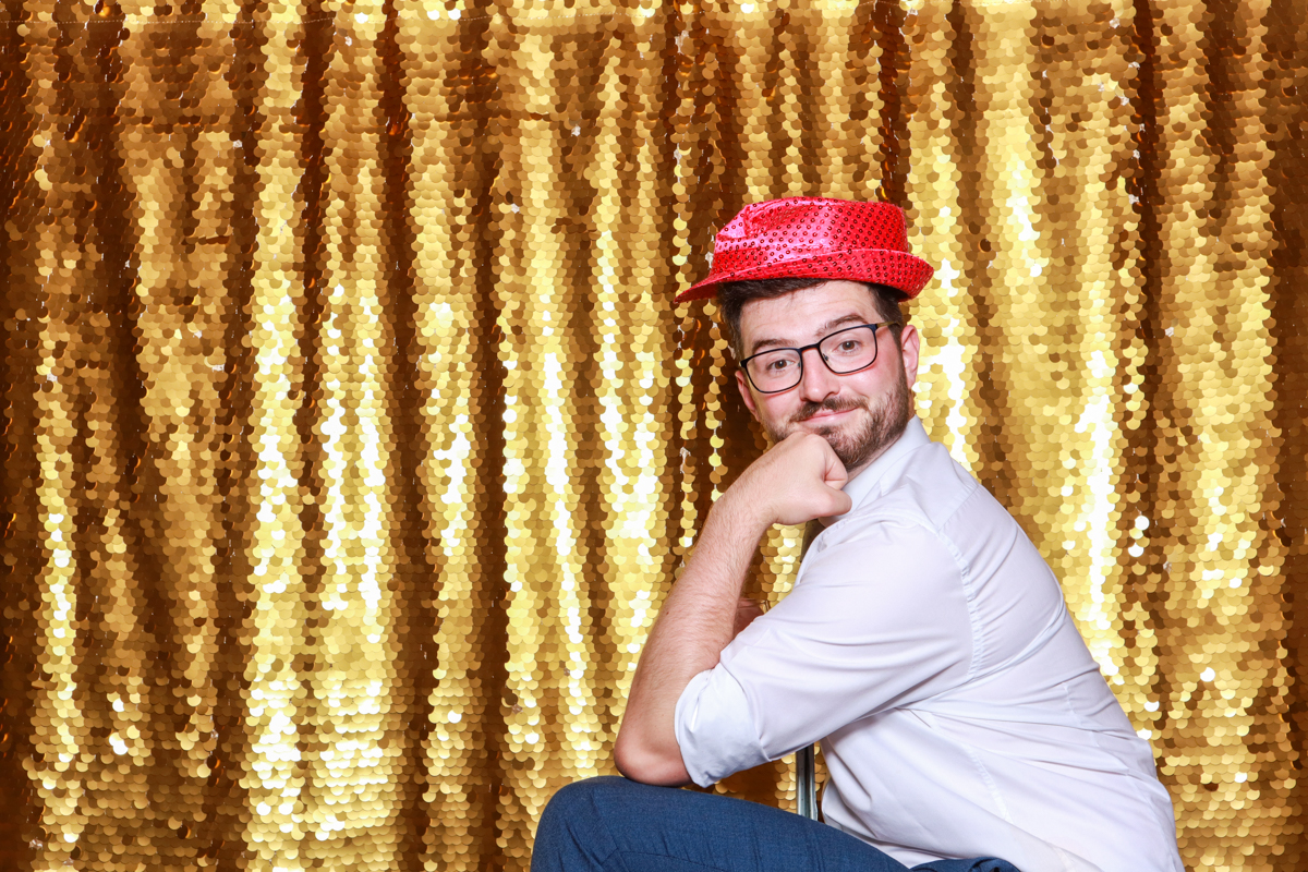 fun guests posing with a gold backdrop for a swallows nest wedding