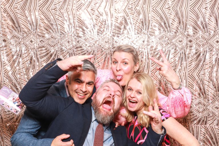 fun group of guests posing for a manor by the lake wedding during the photo booth hire with a bohemian sequins backdrop