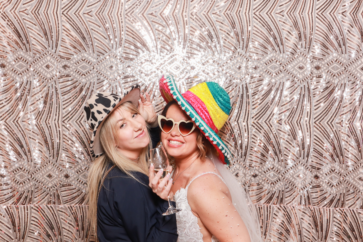 bride posing with her friend during a photo booth reception entertainment, for a manor by the lake wedding