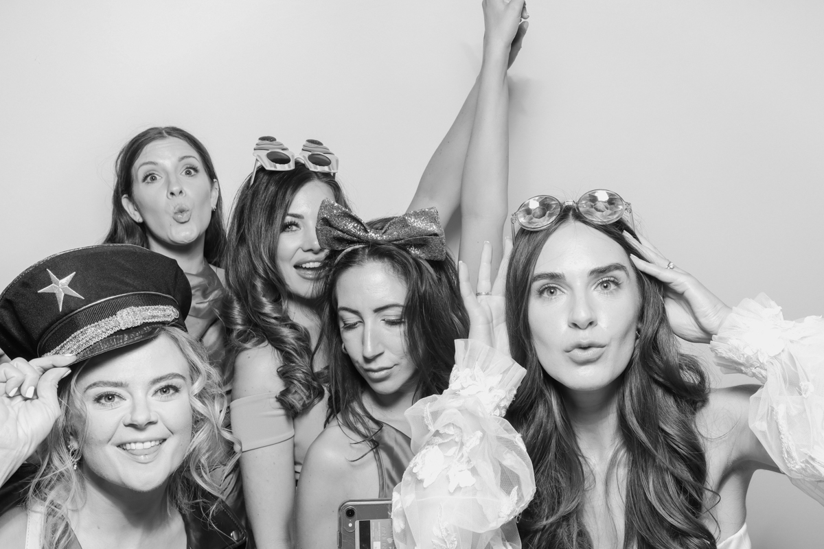 "A group of five guests with various props, smiling and enjoying the Kardashian style photo booth B&W Cotswolds wedding