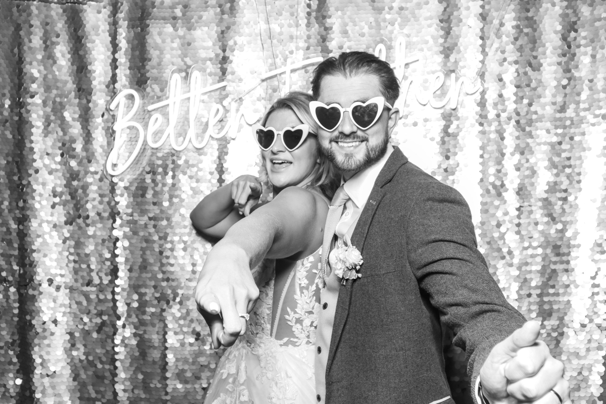 couple with heart shaped glasses posing for their black and white photo booth pictures