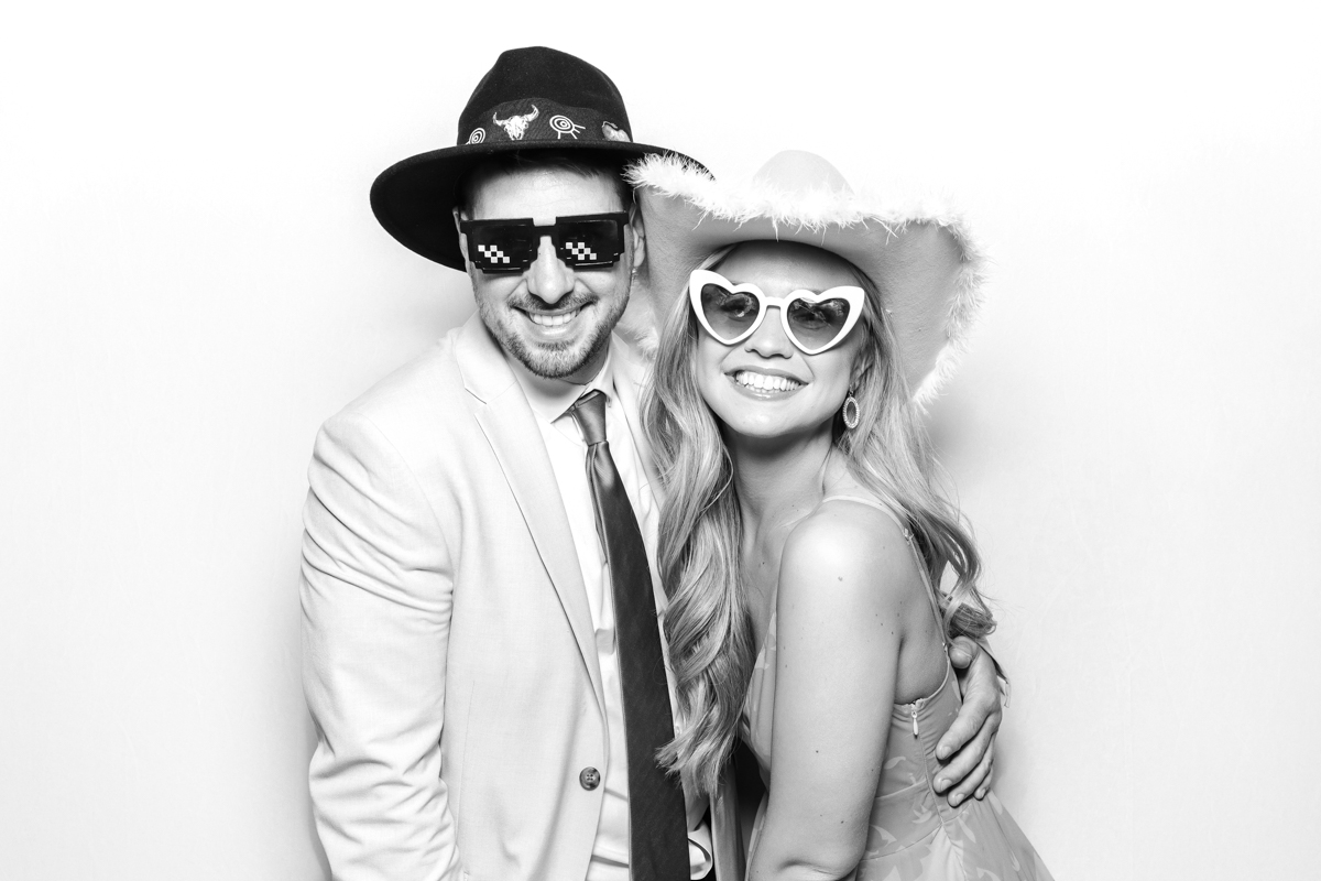 couple posing for a photo booth hire in the cotswolds, wearing fun props