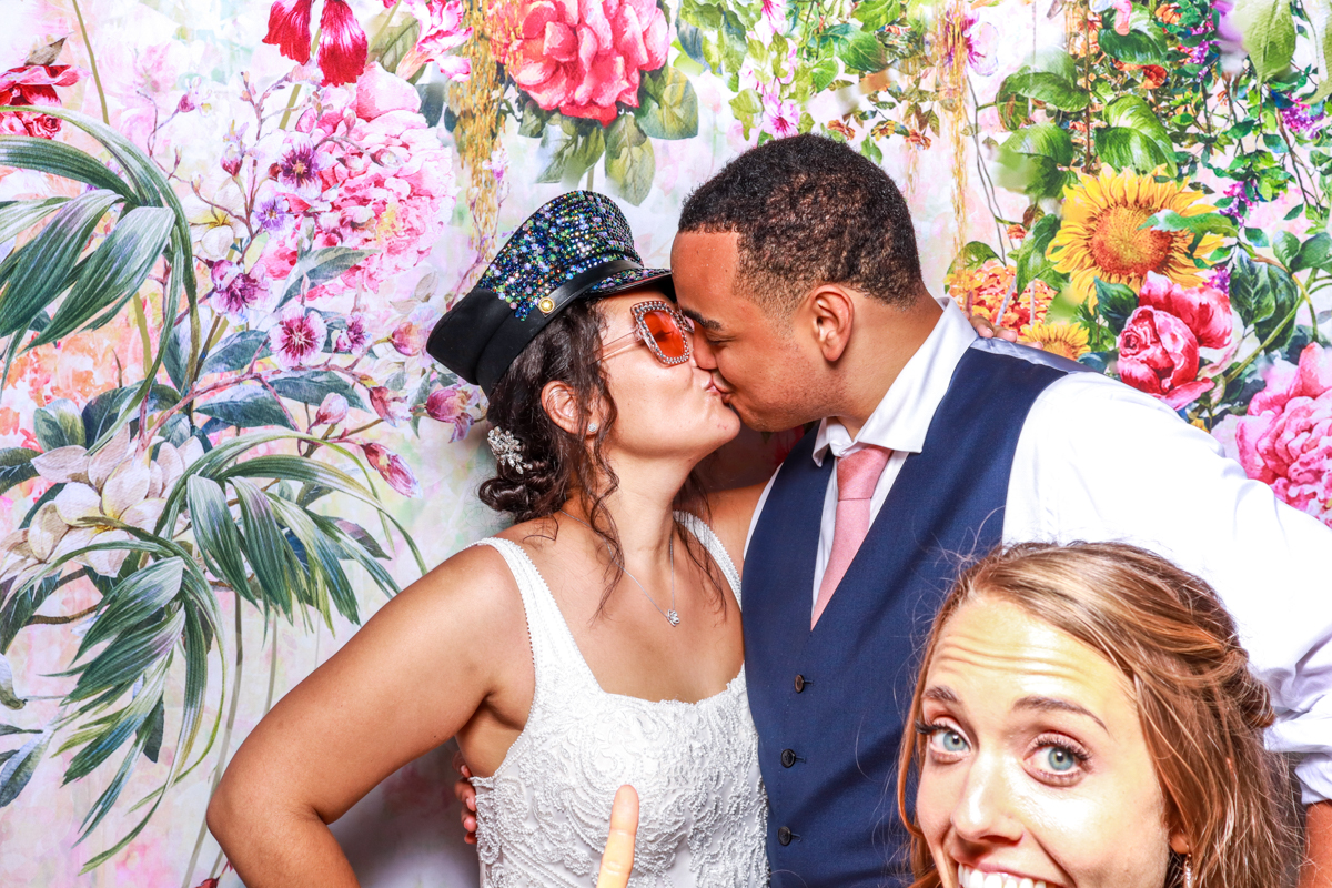 couple kissing with a floral backdrop behind, during the party entertainment at Berkeley Castle