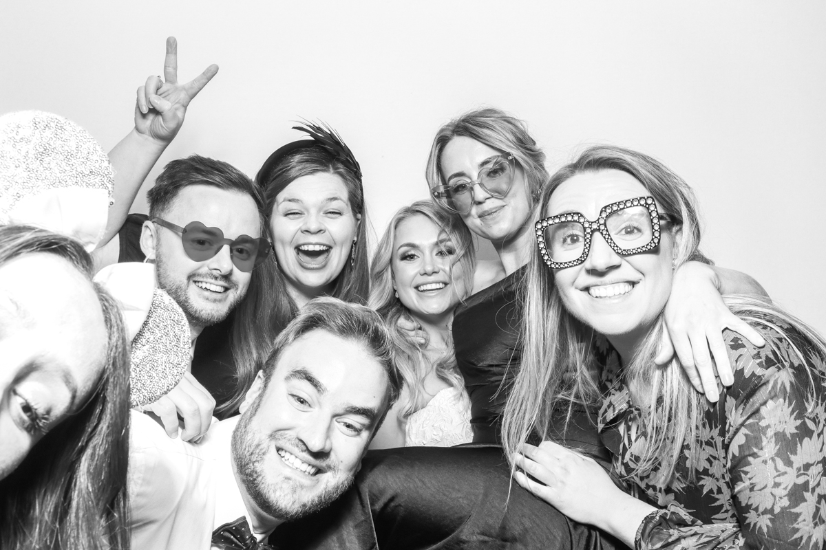 large group of guests posing for a wooden photo booth during the wedding party at Hatherley Manor Hotel 