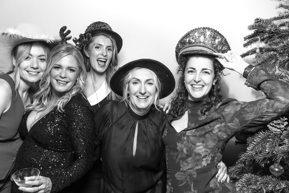 group of ladies posing for a wooden photo booth with a white backdrop at old gore