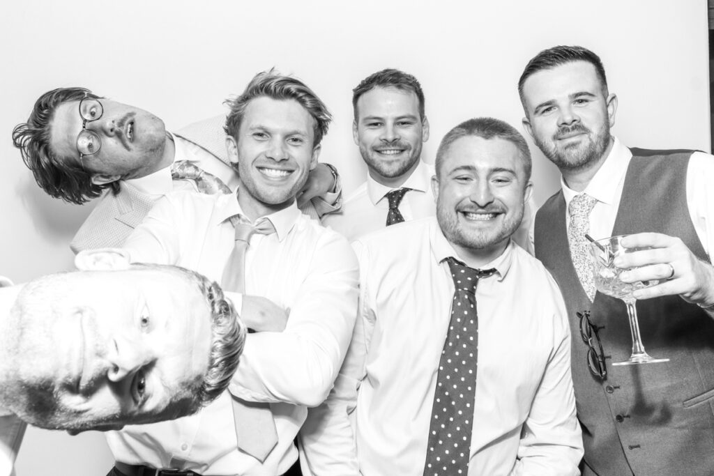 Group of guests enjoying the photo booth, wearing playful hats and sunglasses, capturing a fun and spontaneous moment