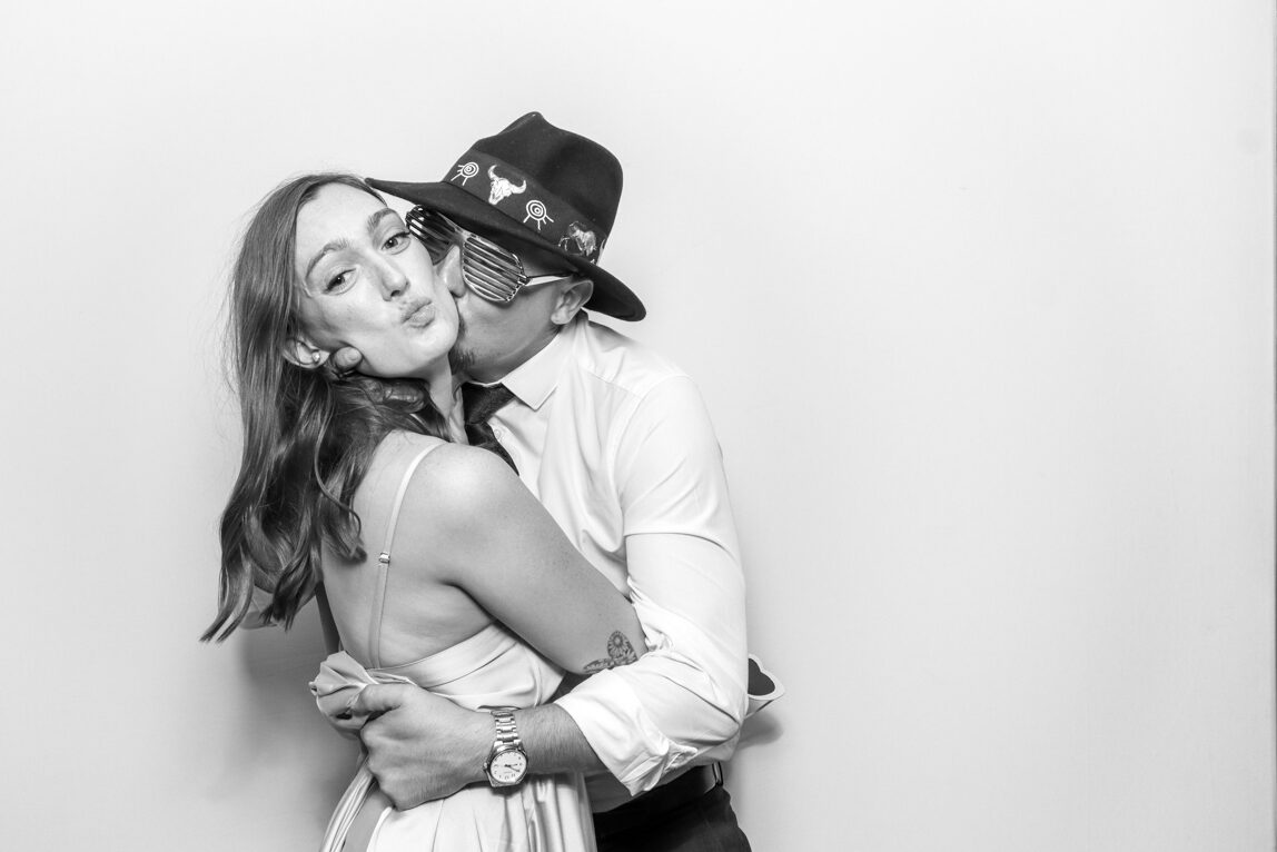 a couple kissing during a photo booth picture at a wedding party, with the kardashian black and white filter 