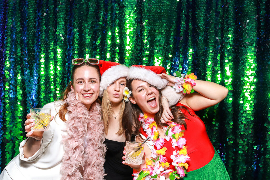 3 girls posing against a green sequins christmas backdrop during their staff party