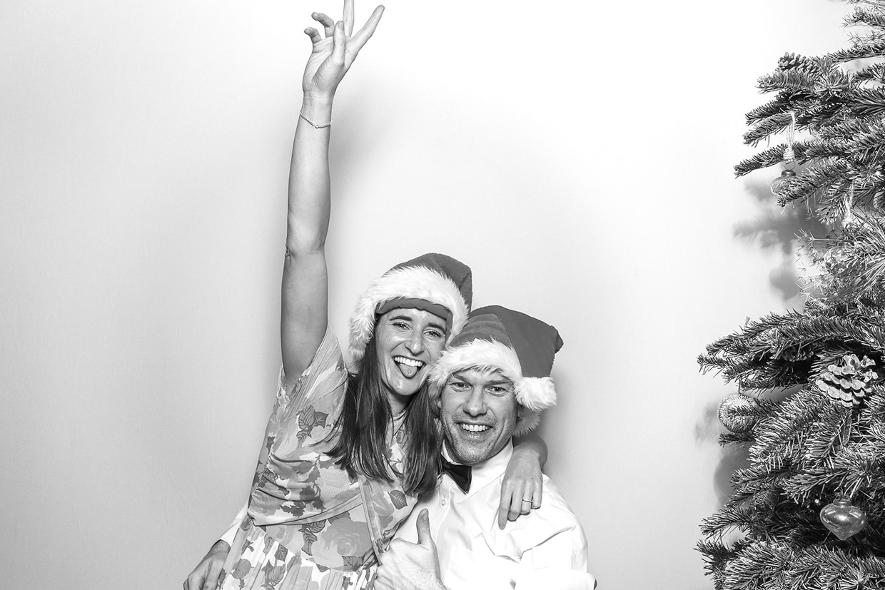 black and white image of couple during a Christmas party photo booth hire with both wearing christmas hats