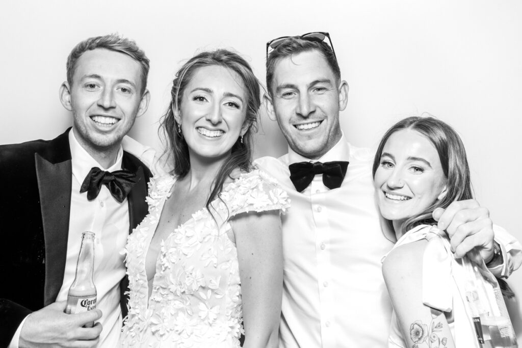 black and white print of 4 guests posing during a wedding party entertainment