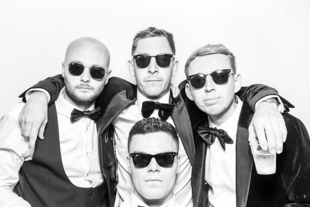 black and white photo of 4 lads posing with sunglasses on during a Luxury photo booth rentals event entertainment