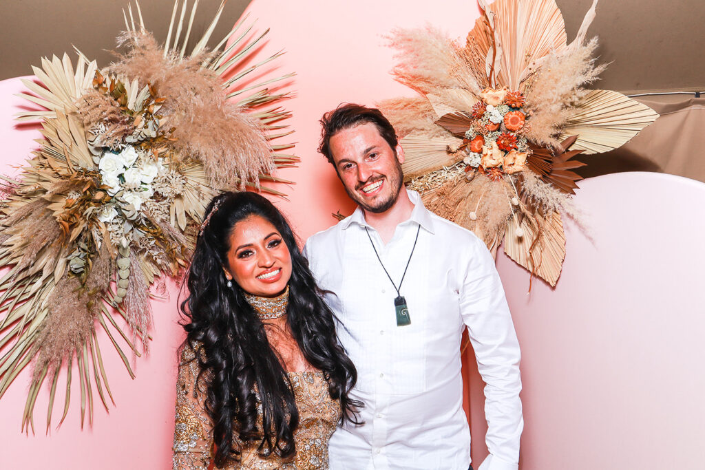 a couple posing for a photo booth rental at euridge manor, with a summer arches backdrop 