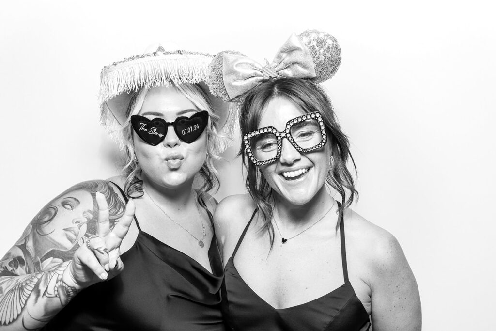 portrait of 2 ladies wearing props against a white backdrop for a kardashian photography style, during a corporate event rental