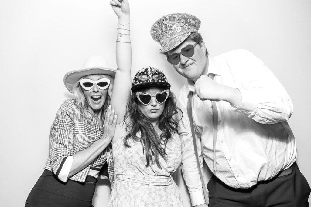 3 guests posing with props and hats while having fun during a corporate party entertainment