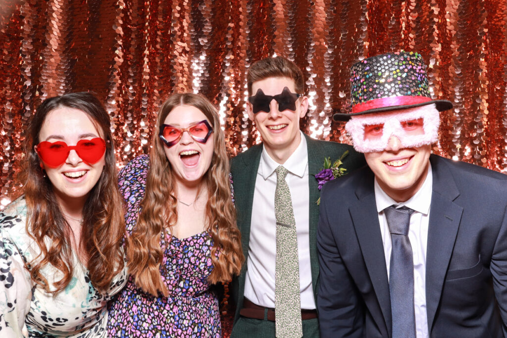 large group of guests wearing fun props and hats posing against a champagne sequins backdrop during a brand event for a party rental 