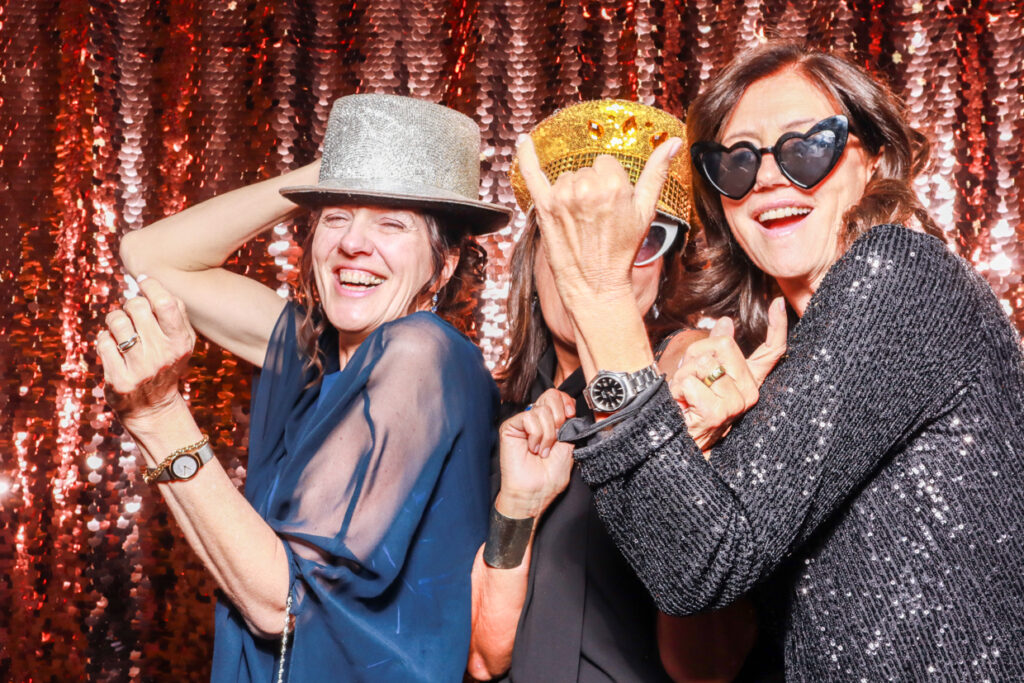 guests posing and having lots of fun during a well organised corporate event , posing against a champagne sequins backdrop for mad hat photo booth rental in cotswolds